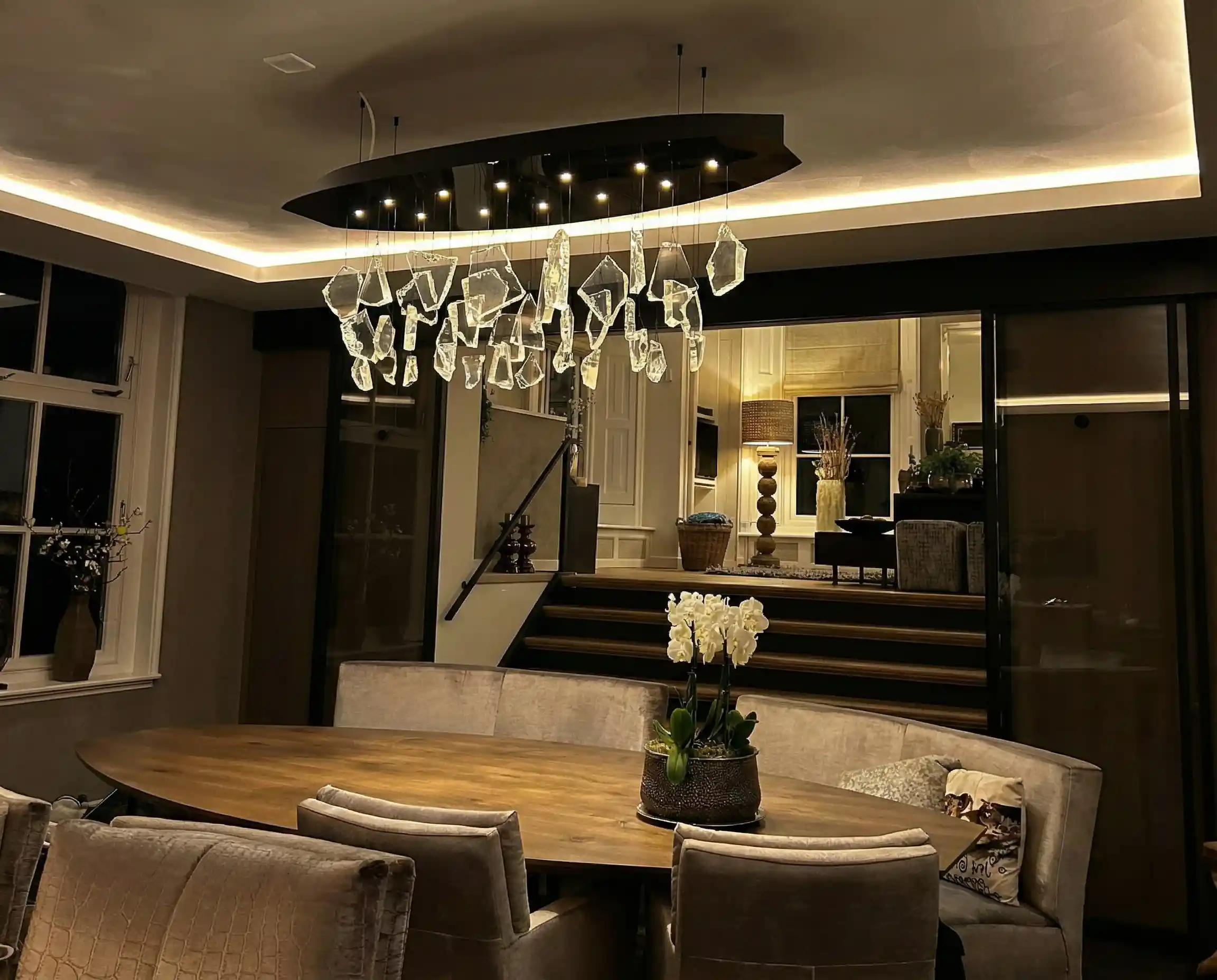 Warm witte LED-strip in koof zorgt voor zachte indirecte plafondverlichting in moderne eetkamer met warme uitstraling.