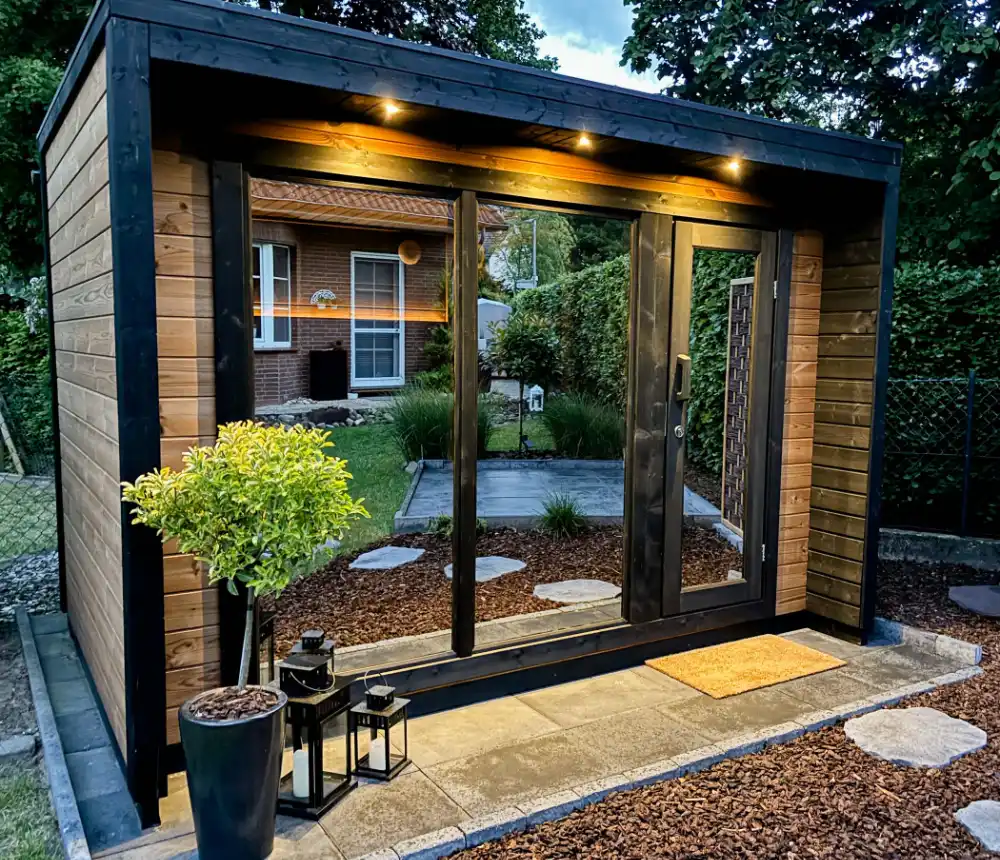 Buitensauna met meerdere LED spots onder de dakrand die de entree warm en uitnodigend verlichten